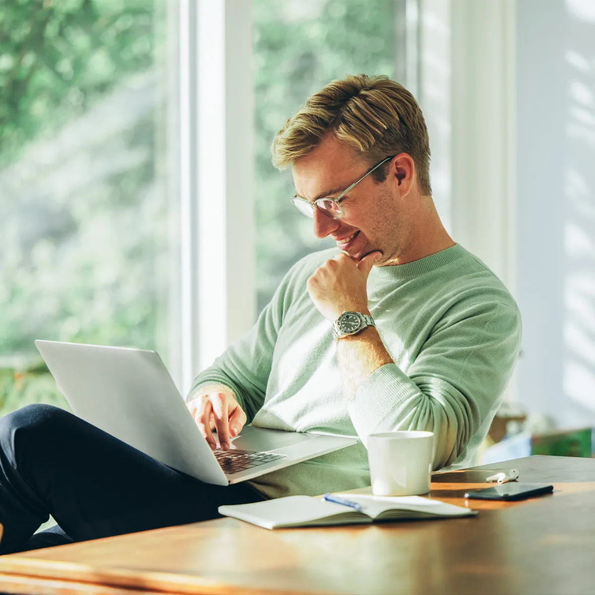 Mann am Laptop sitzt entspannt am Schreibtisch