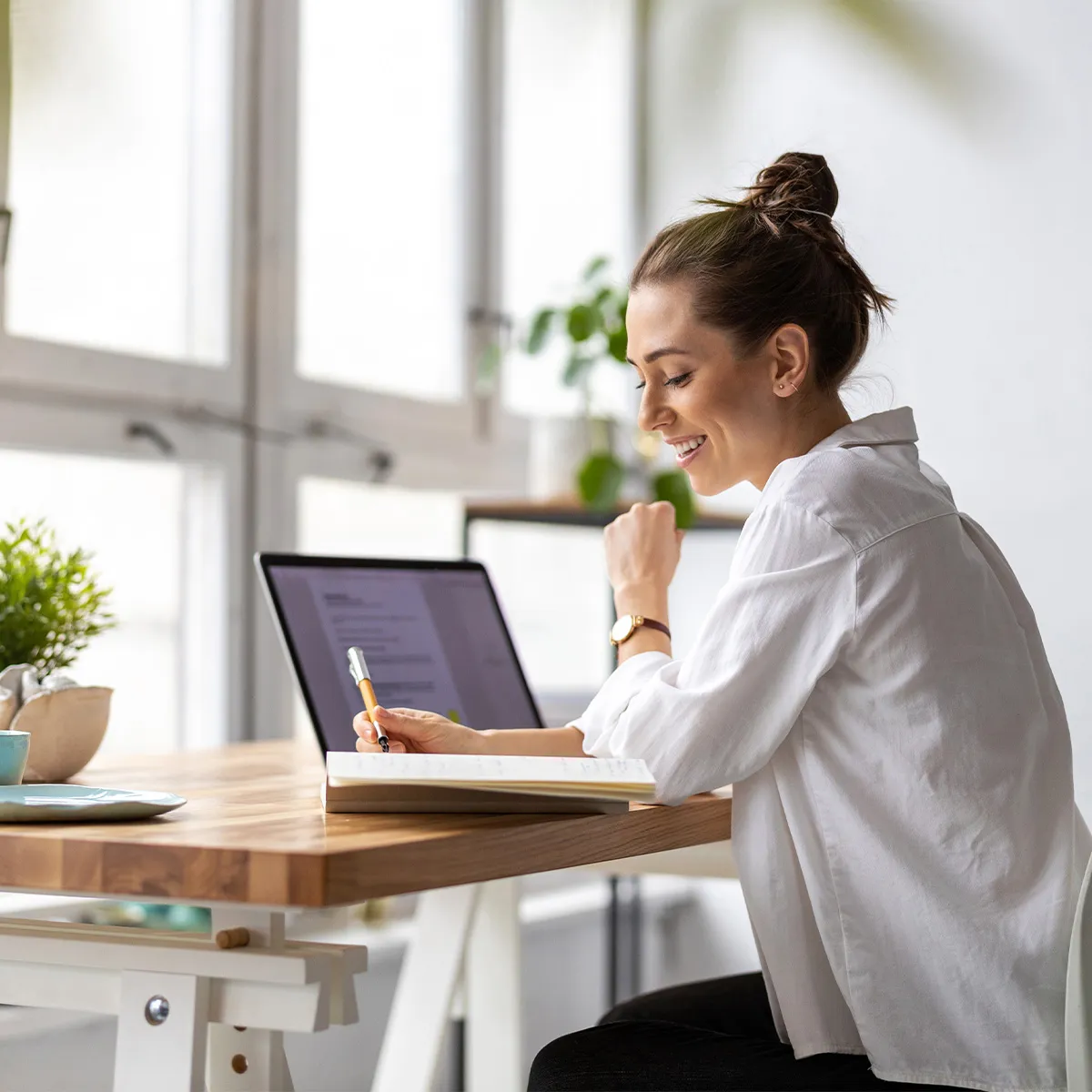 Frau am Schreibtisch notiert sich etwas im Notizbuch
